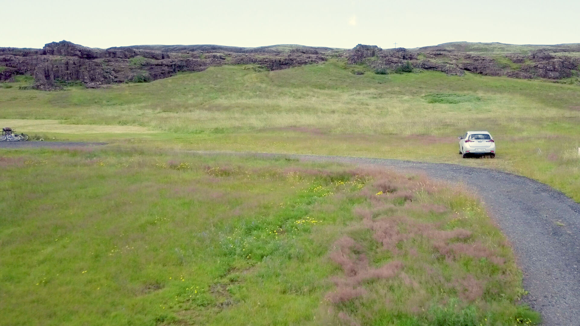 Gravel access road and the existing house at Riftún with the lava escarpment behind
